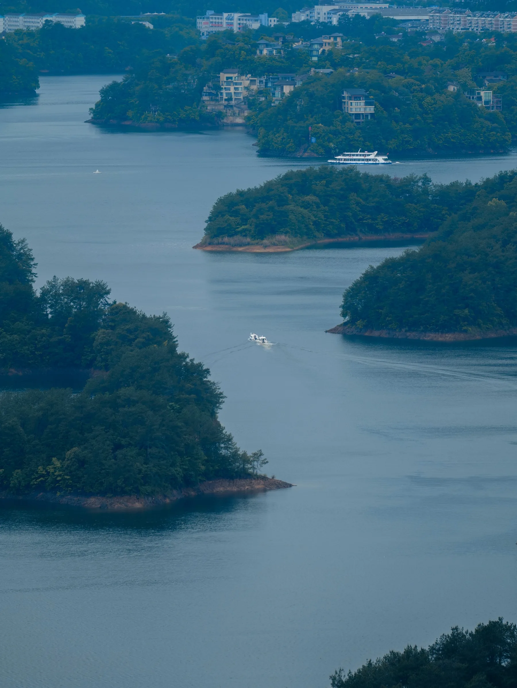 Boats moving through blue channels between wooded islands and lakeside homes