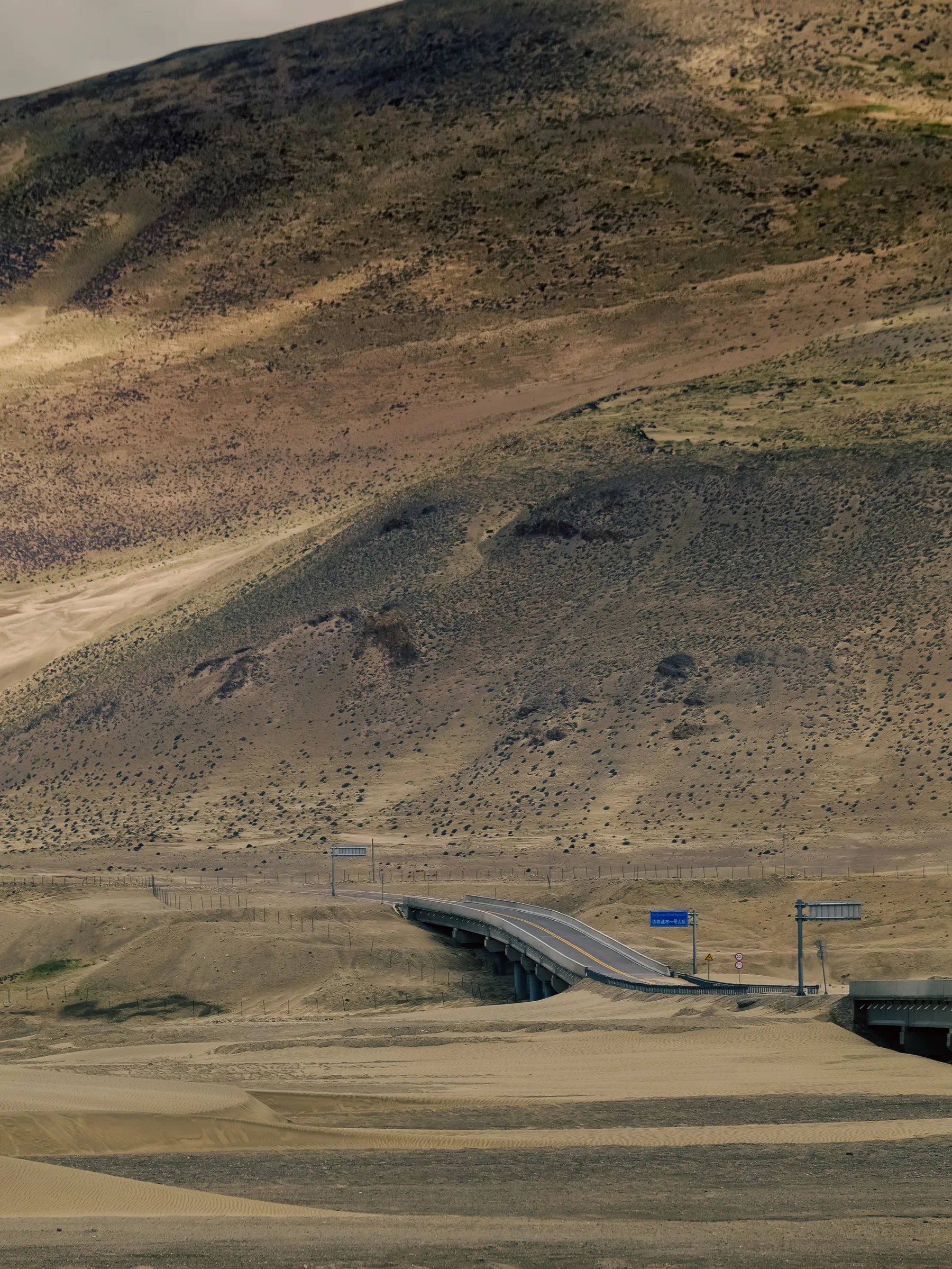 A solitary road cutting through a wide and barren mountain plateau