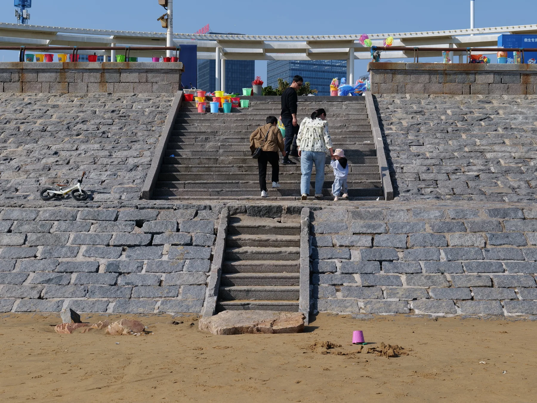 People climbing broad stone steps from a sandy shoreline