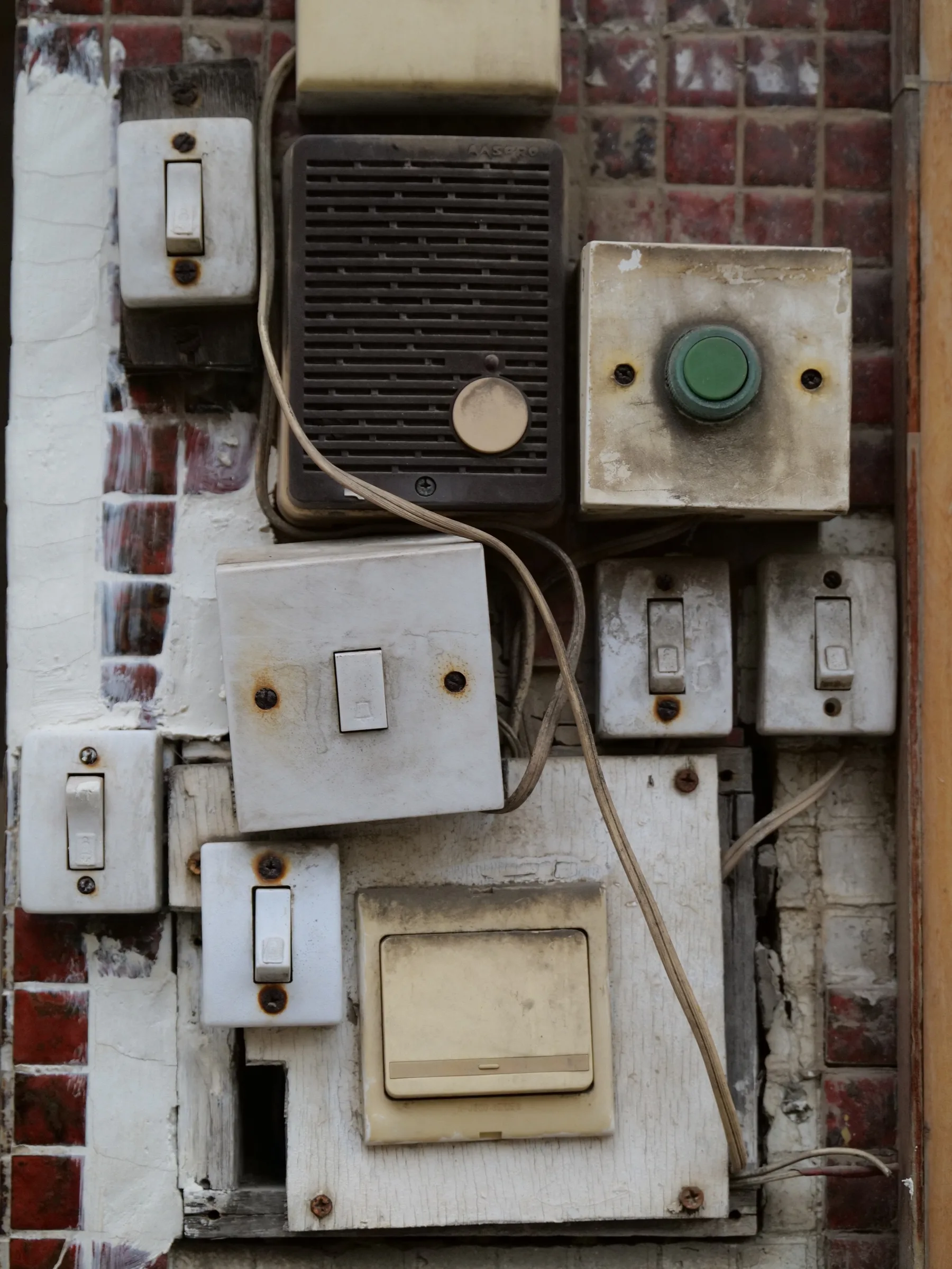 A weathered arrangement of switches and electrical boxes on brick