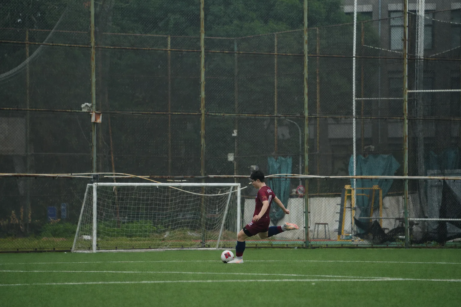 A football player striking the ball on an outdoor pitch